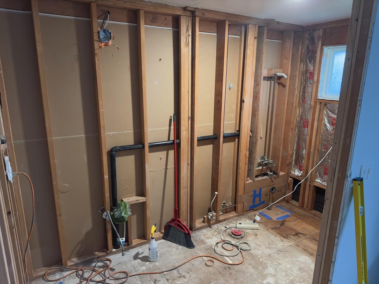 A photo of a gutted bathroom with the inner walls exposed.