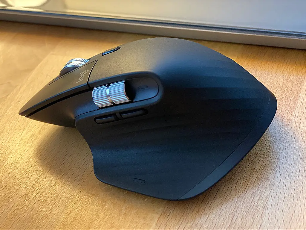 Logitech mouse sitting on a wood desk.