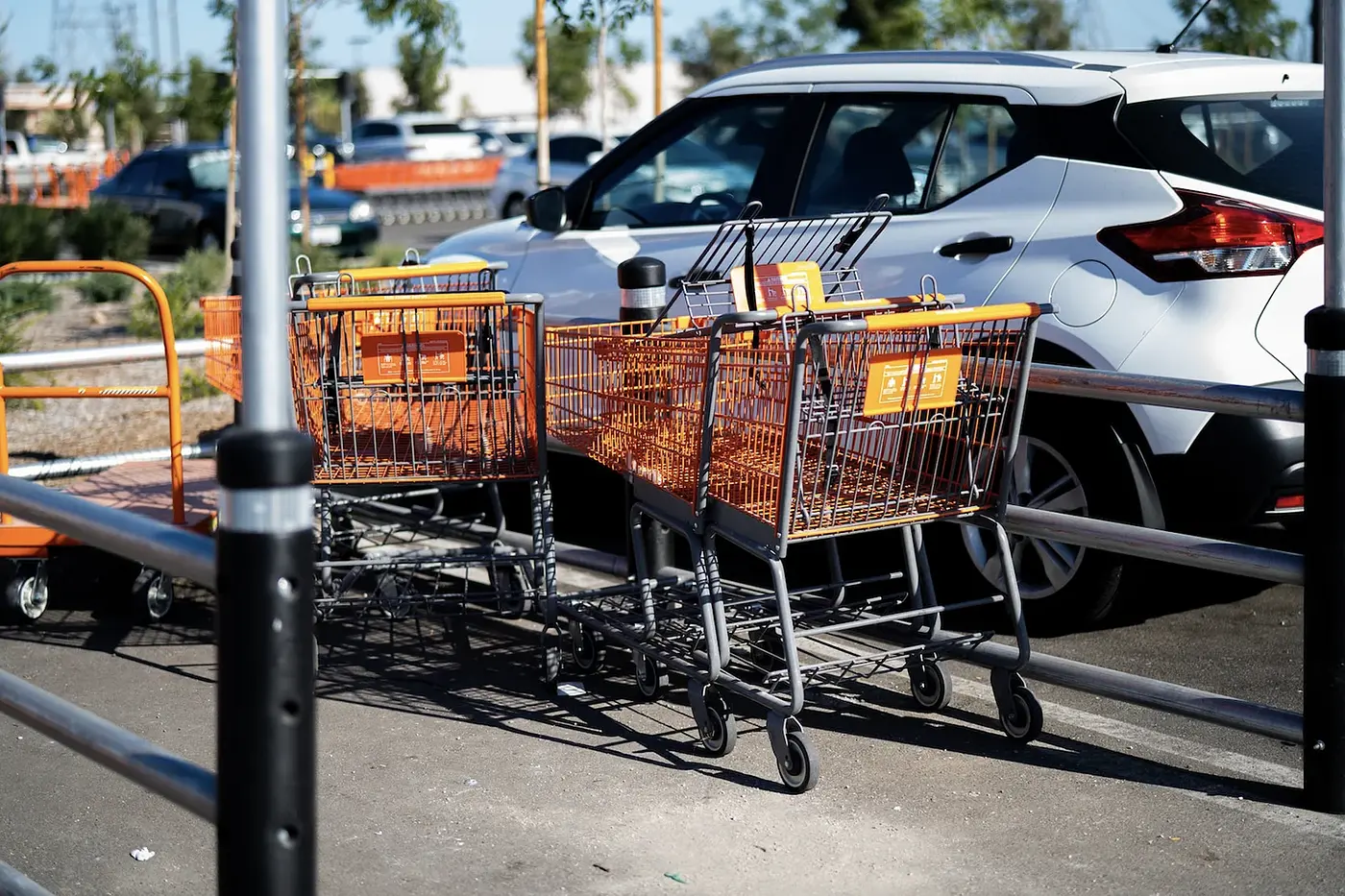 A photo of a grocery cart return with a white car next to it.