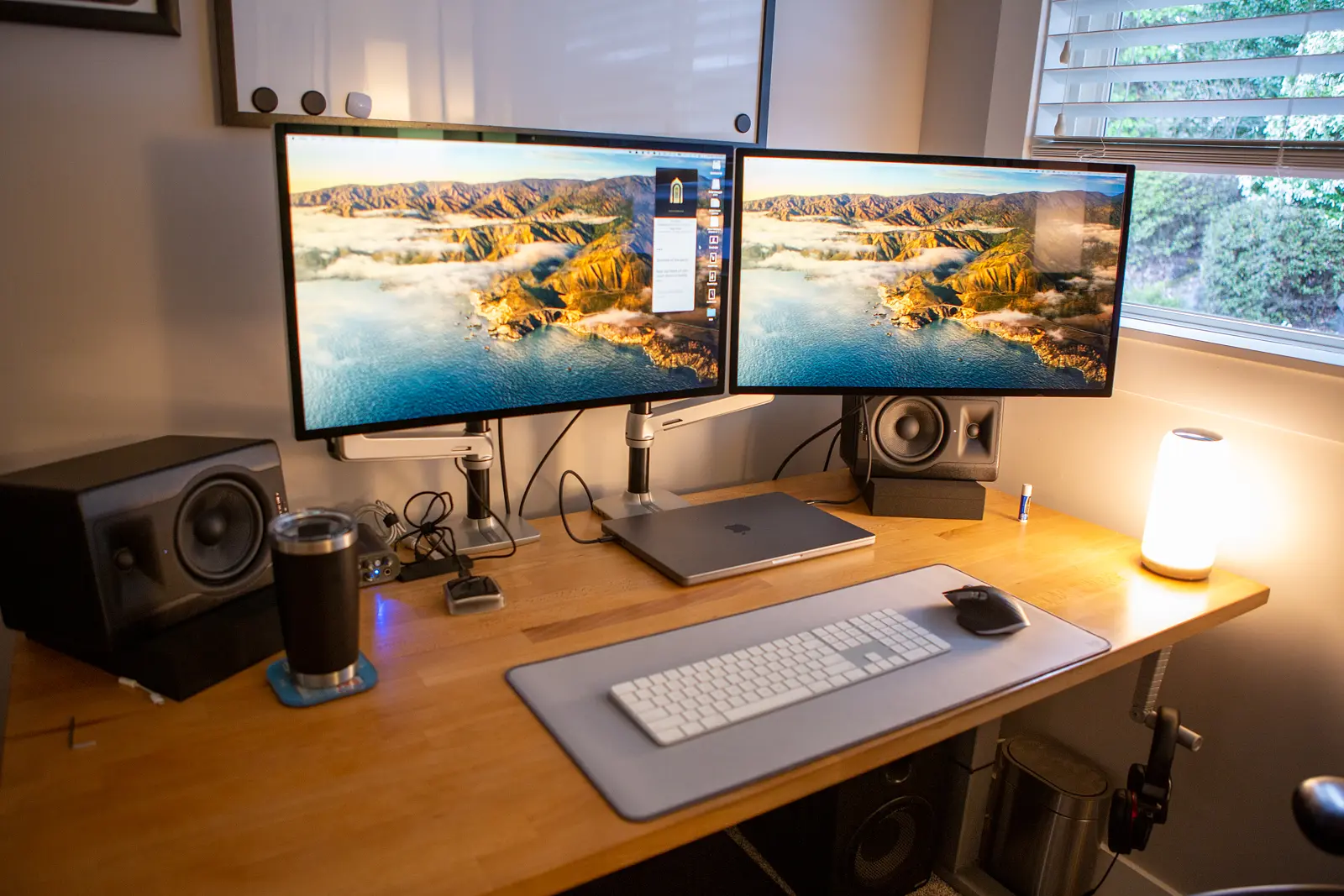 2 Studio Displays mounted to a wooden desk.