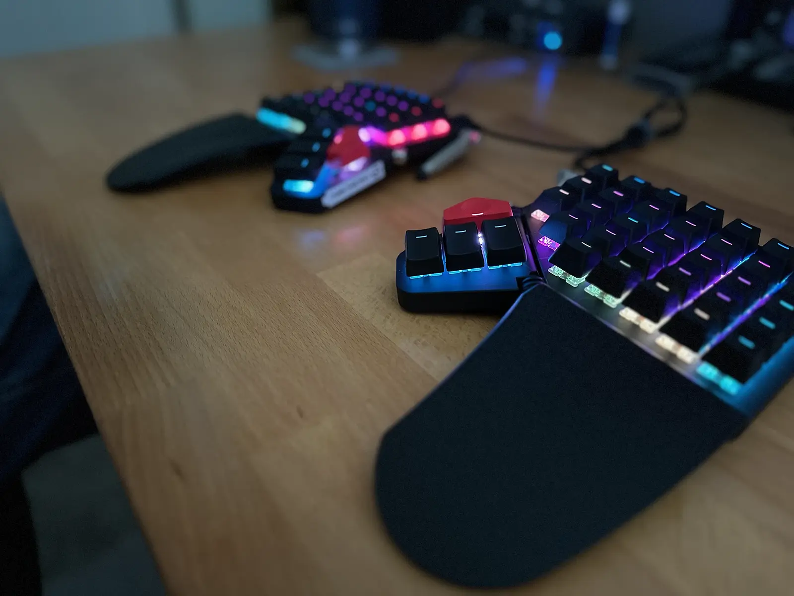 A black Moonlander keyboard on a wood desk. The photo is taken from the right side with a narrow depth of field.