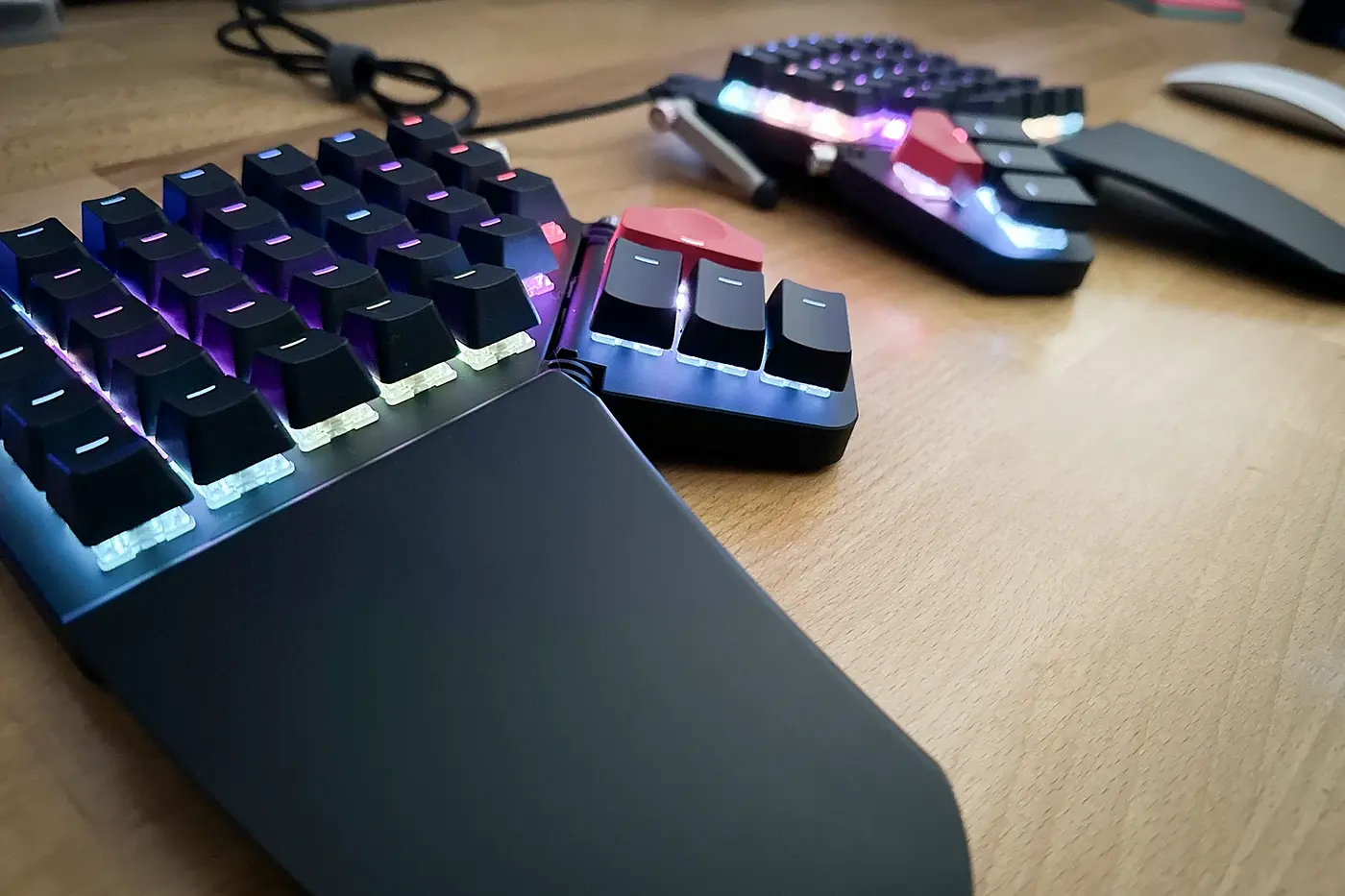 A photograph of a black ZSA Moonlander keyboard taken from the left side. It sits on a wood desk.